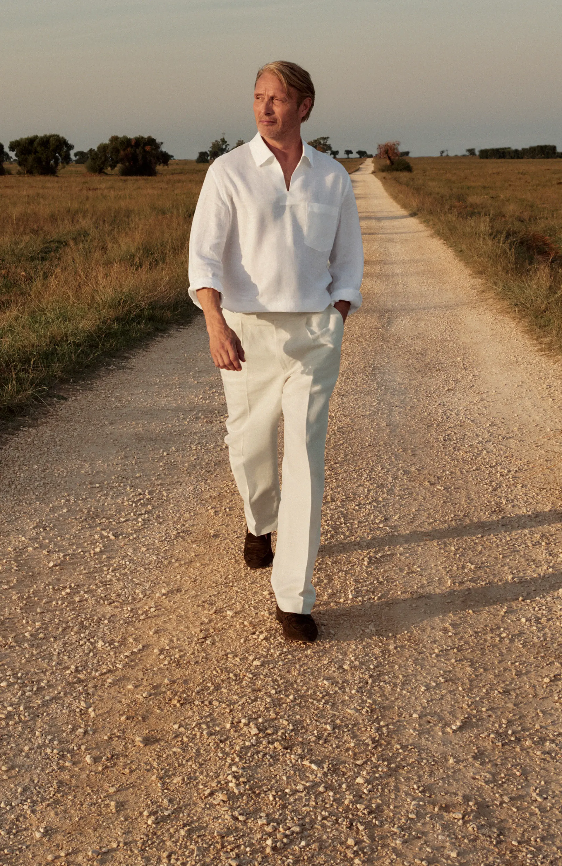 Mads Mikkelsen wearing a refined linen outfit paired with suede loafers from the ZEGNA SS25 collection.