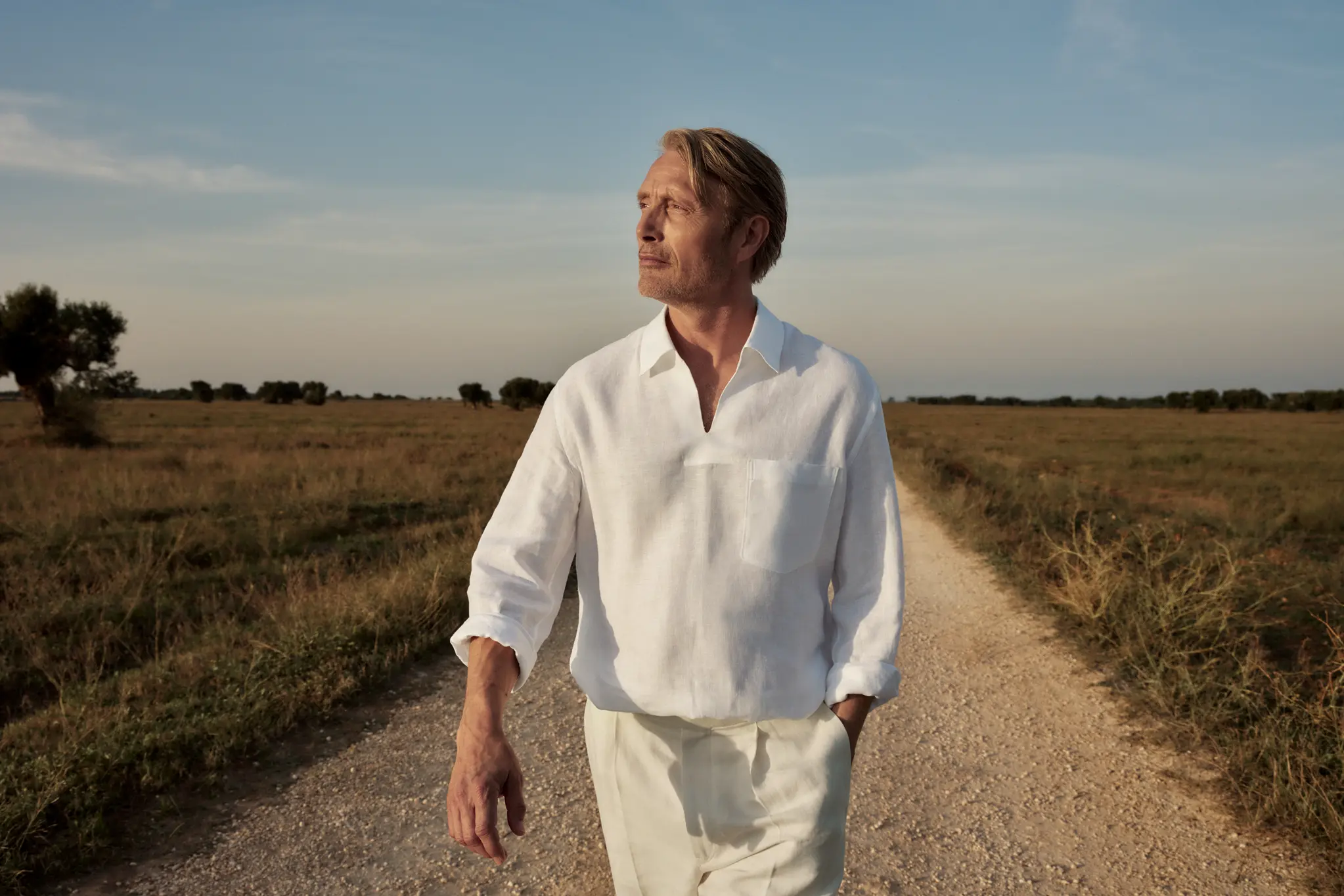 Image 1: Mads Mikkelsen wearing a refined linen outfit paired with suede loafers from the ZEGNA SS25 collection.