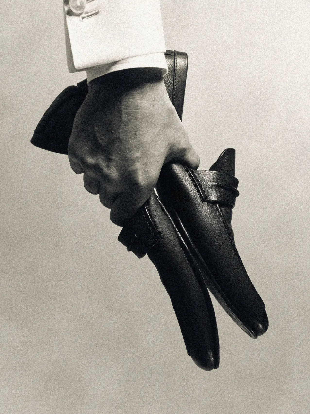 Image 4: Hand holding a pair of ZEGNA Mocassin loafers, showcasing their elegant craftsmanship.