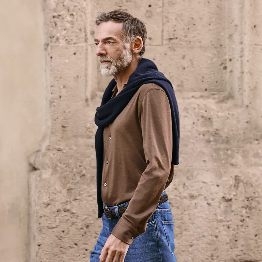 Mann in einem edlen Freizeitlook, mit Kaschmirpullover und Jeans aus der ZEGNA FW25 Kollektion.