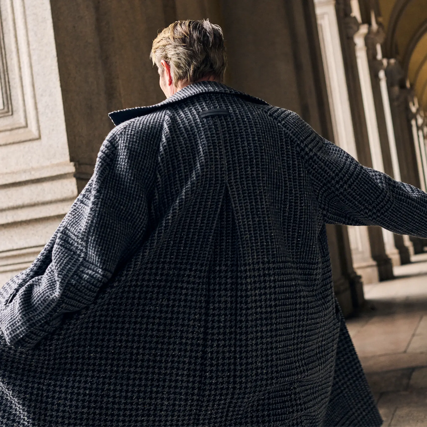 Mads Mikkelsen portant un manteau et un costume de style Torino assortis à motif pied-de-poule de la collection FW25 de ZEGNA.