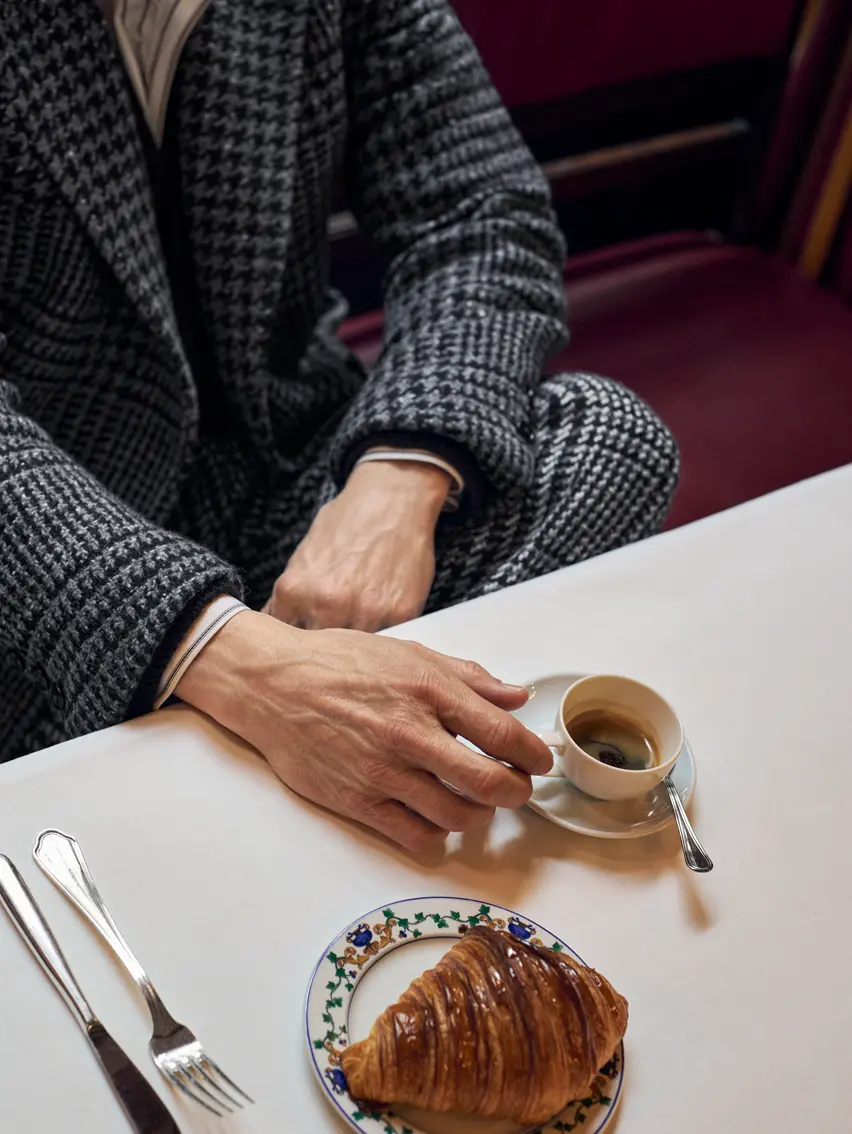 Close-up of Mads Mikkelsen enjoying coffee in a classic tailored look, from the ZEGNA FW25 collection.