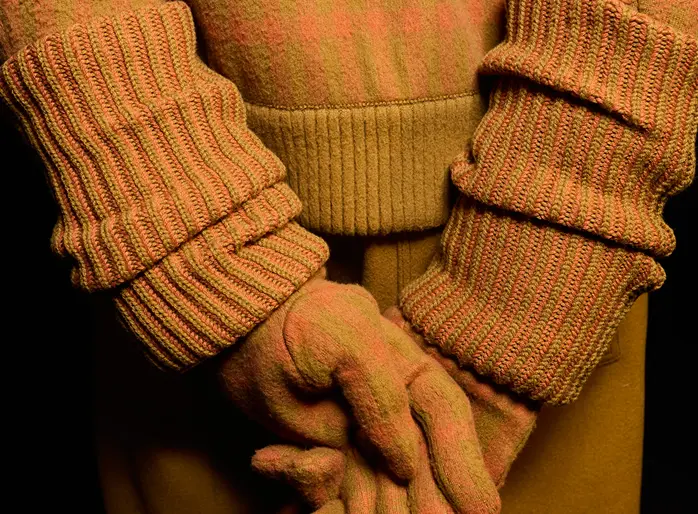 Un homme en tenue cachemire orange ZEGNA avec les gants assortis.