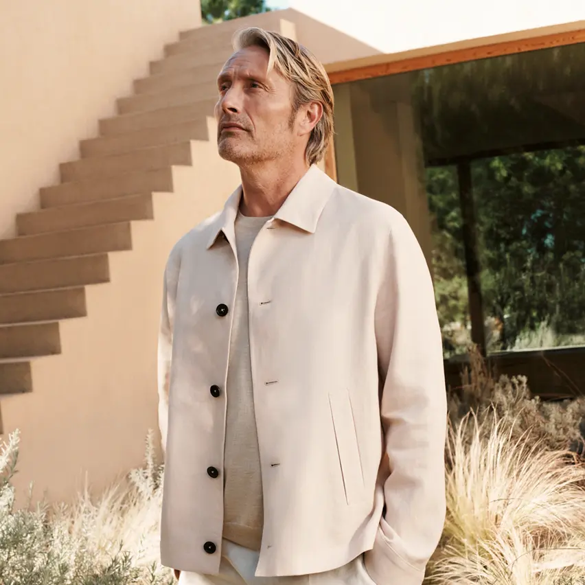 Der Schauspieler Mads Mikkelsen in einem ZEGNA Ensemble, bestehend aus einem hellbeigen Overshirt und einer weißer Leinenhose.