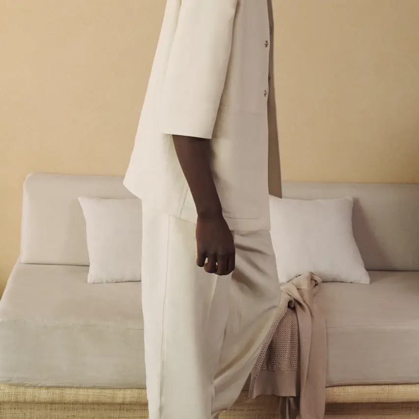 Ein Model in einem ZEGNA Ensemble mit einer weißen Leinenstrickjacke und einer locker sitzenden Leinenhose.