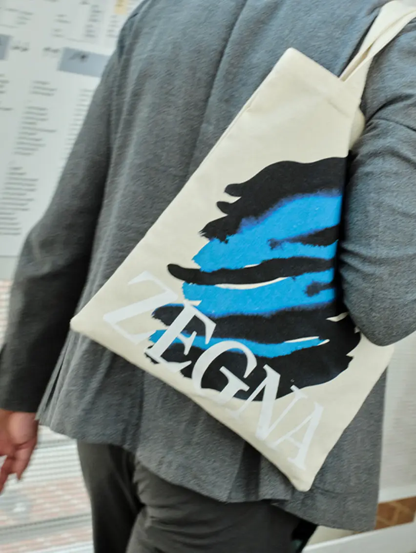 Man carrying the tote bag with ZEGNA and Art Basel logo.