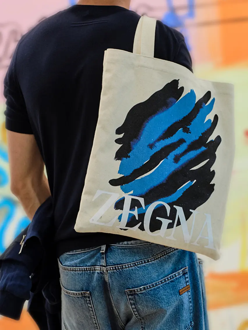 Man carrying the tote bag with ZEGNA and Art Basel logo.