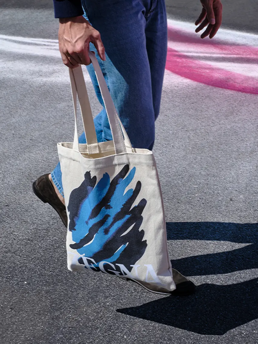 Man carrying the tote bag with ZEGNA and Art Basel logo.