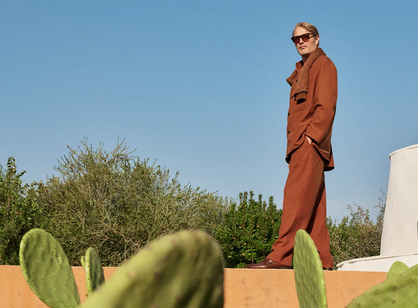 Mads Mikkelsen portant un ensemble en lin raffiné dans un ton tellurien avec des mocassins en cuir de la collection SS25 de ZEGNA.