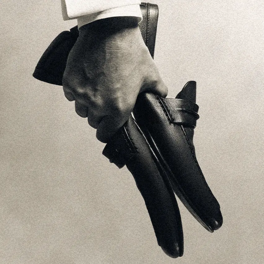 Hand holding a pair of ZEGNA Mocassin loafers, showcasing their elegant craftsmanship.