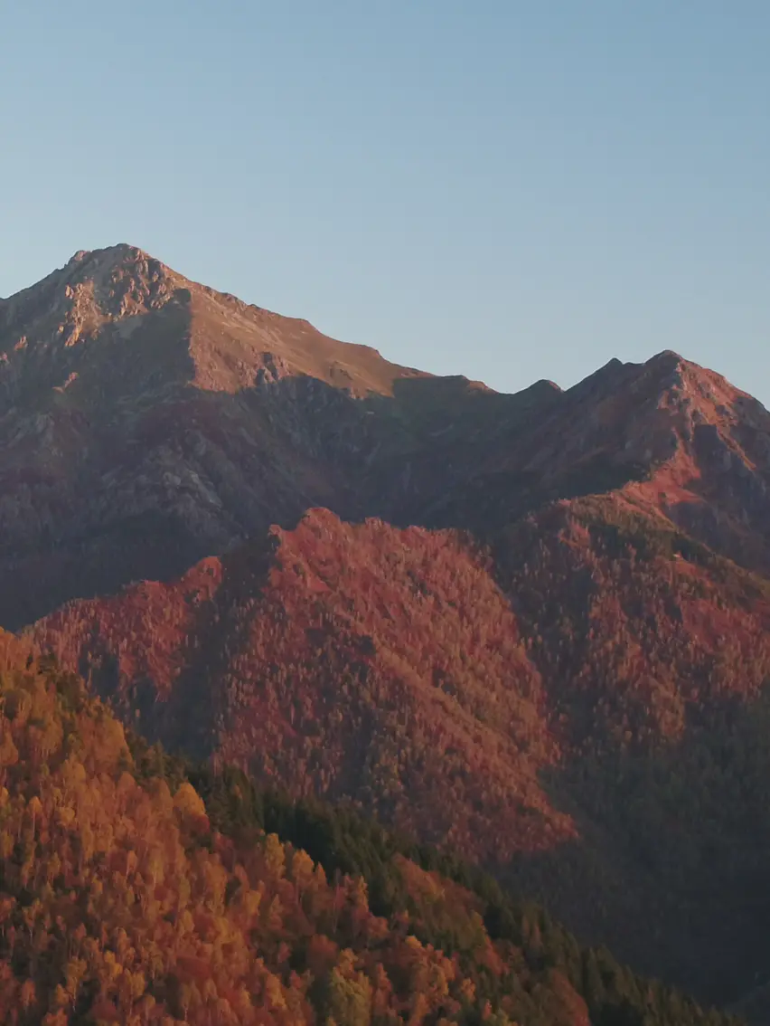 Panoramic view of a natural landscape with layered hills and warm light, evoking a sense of depth and quiet atmosphere.