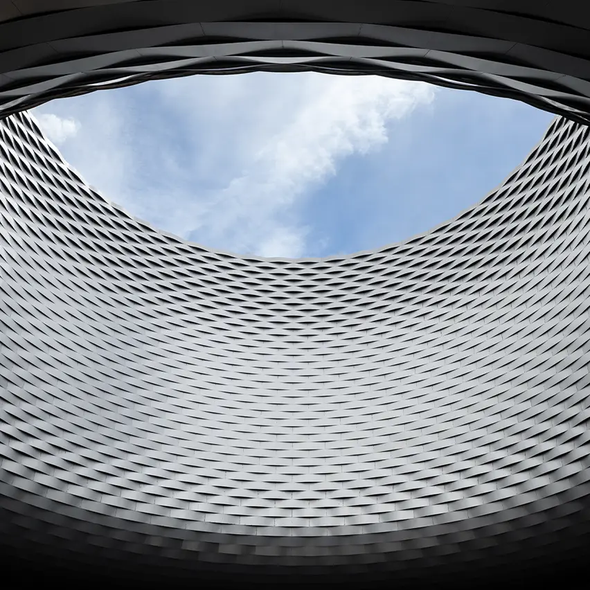 Interior view of the Art Basel venue, showing the dramatic circular opening and textured architectural structure of Messe Basel.