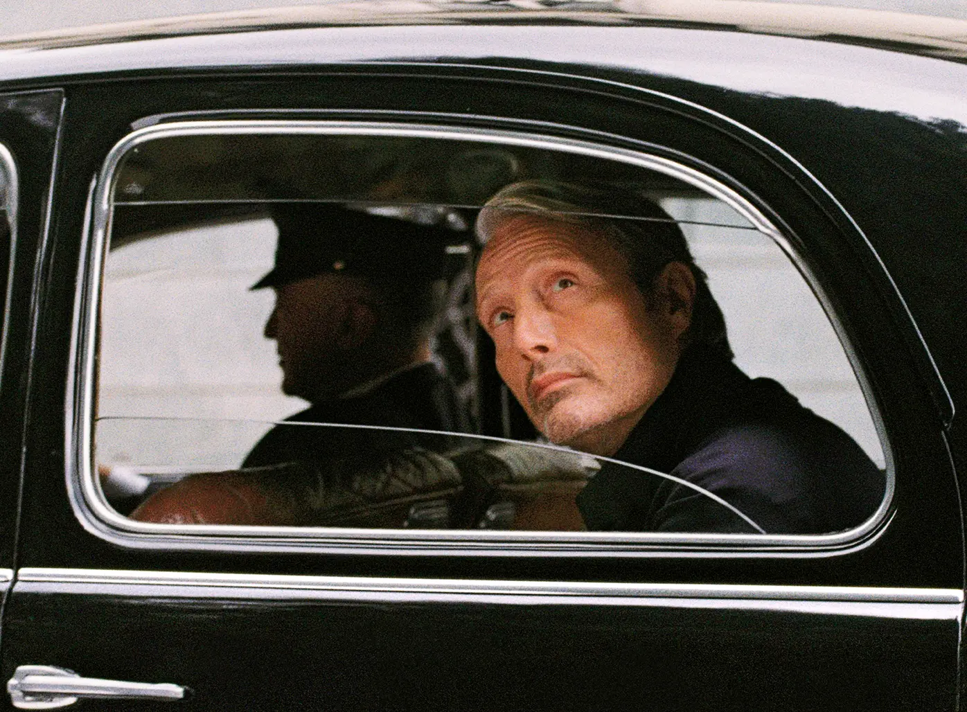 Close-up of Mads Mikkelsen inside a black car, wearing a refined ZEGNA look.
