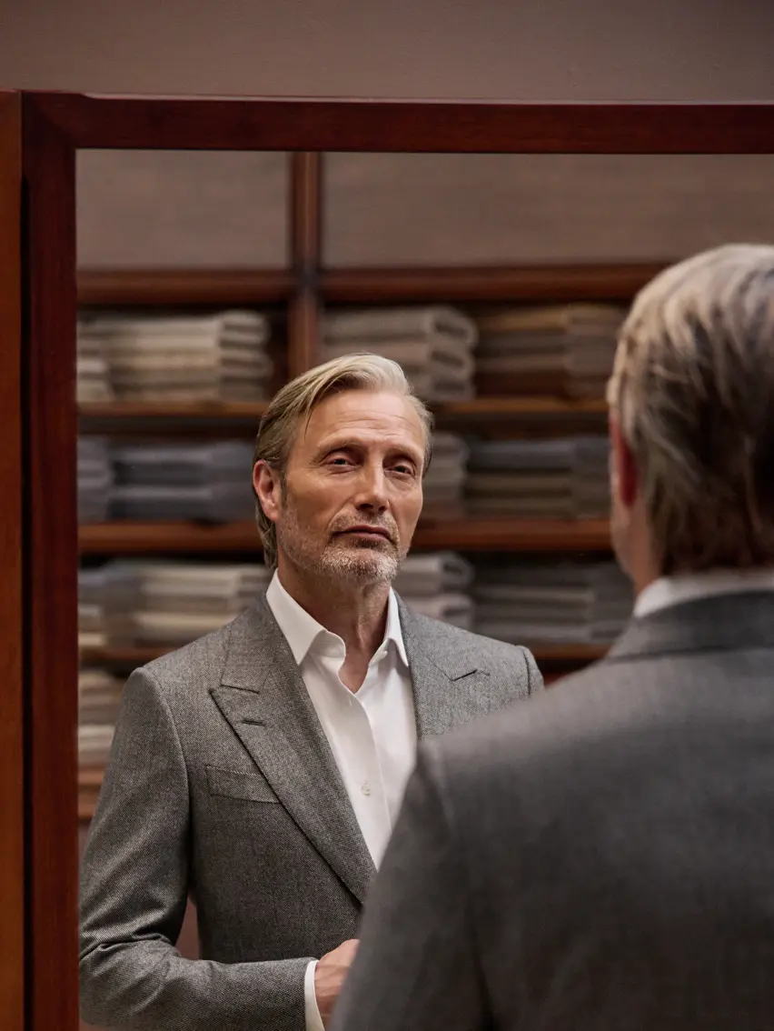 Mads Mikkelsen, vêtu d’un élégant costume gris ZEGNA, lors d’un rendez-vous avec son couturier.