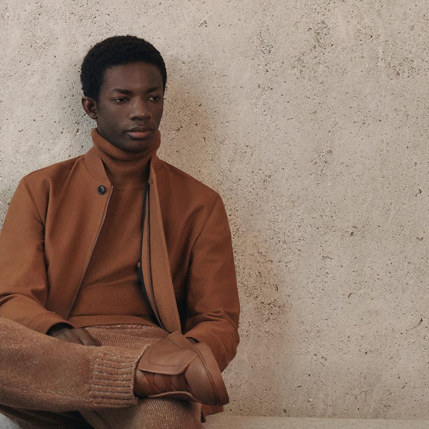 Un homme assis portant le blouson aviateur couleur Foliage Elements Oasi Cashmere de ZEGNA.