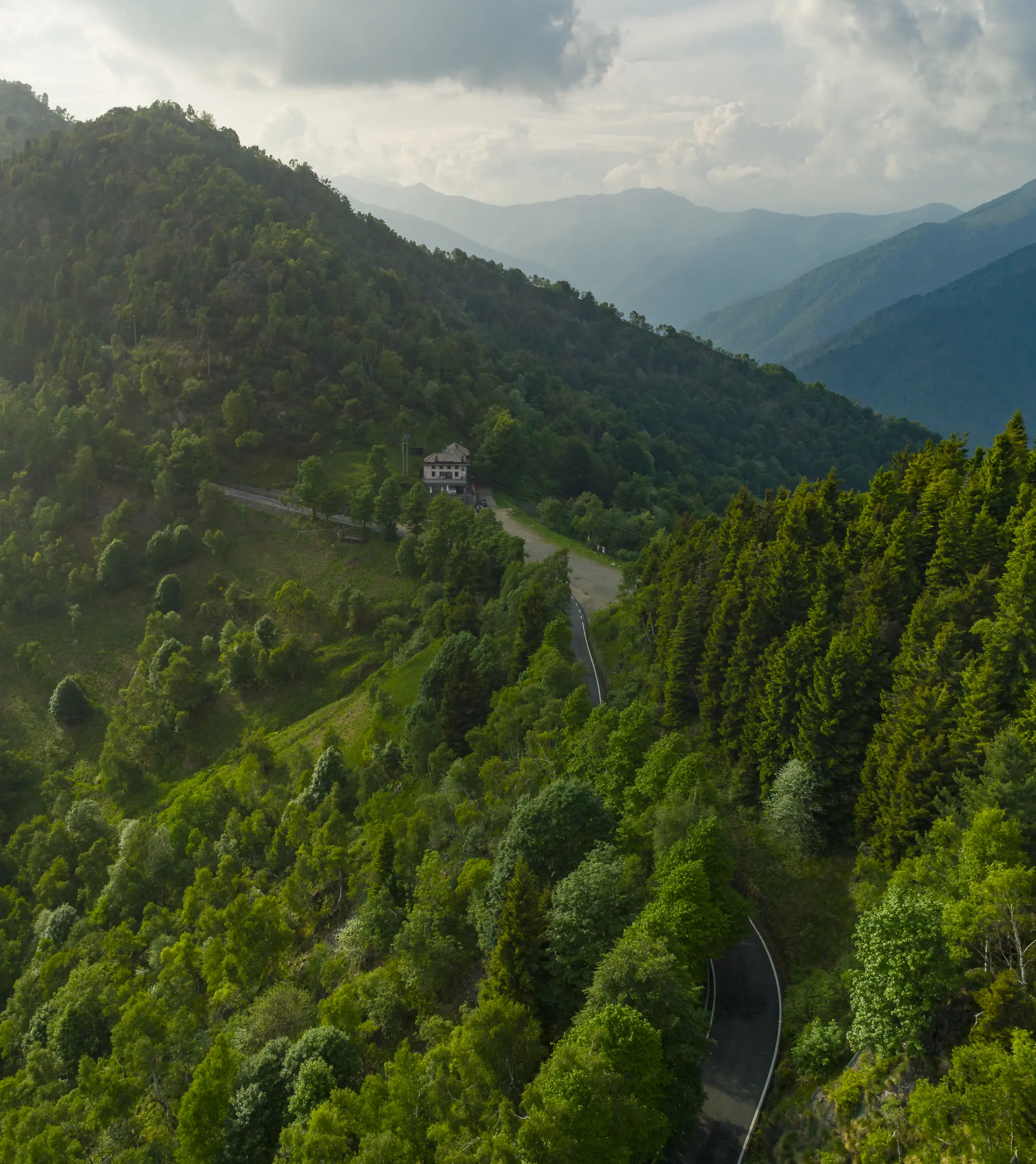Panoramic view of Bocchetta di Luvera in Oasi Zegna, historic mountain pass and scenic transhumance route surrounded by forested hills.