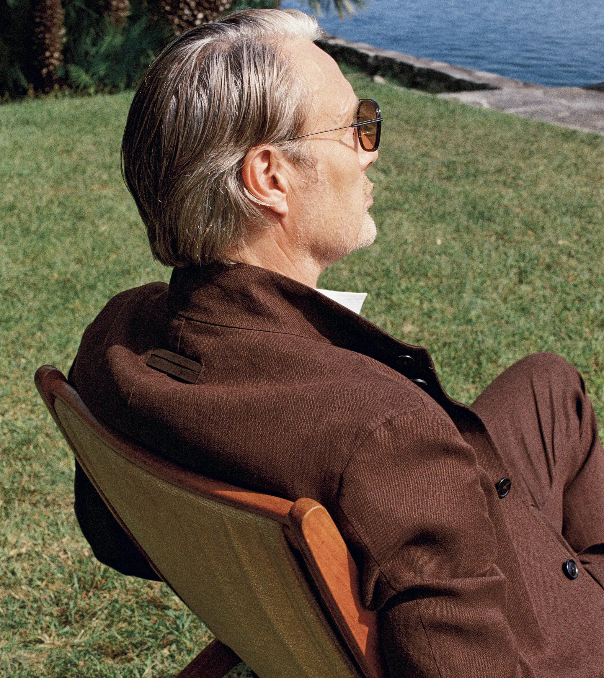 Mads Mikkelsen wearing a refined look from the ZEGNA Spring Summer 2026 collection in a lakeside garden setting.