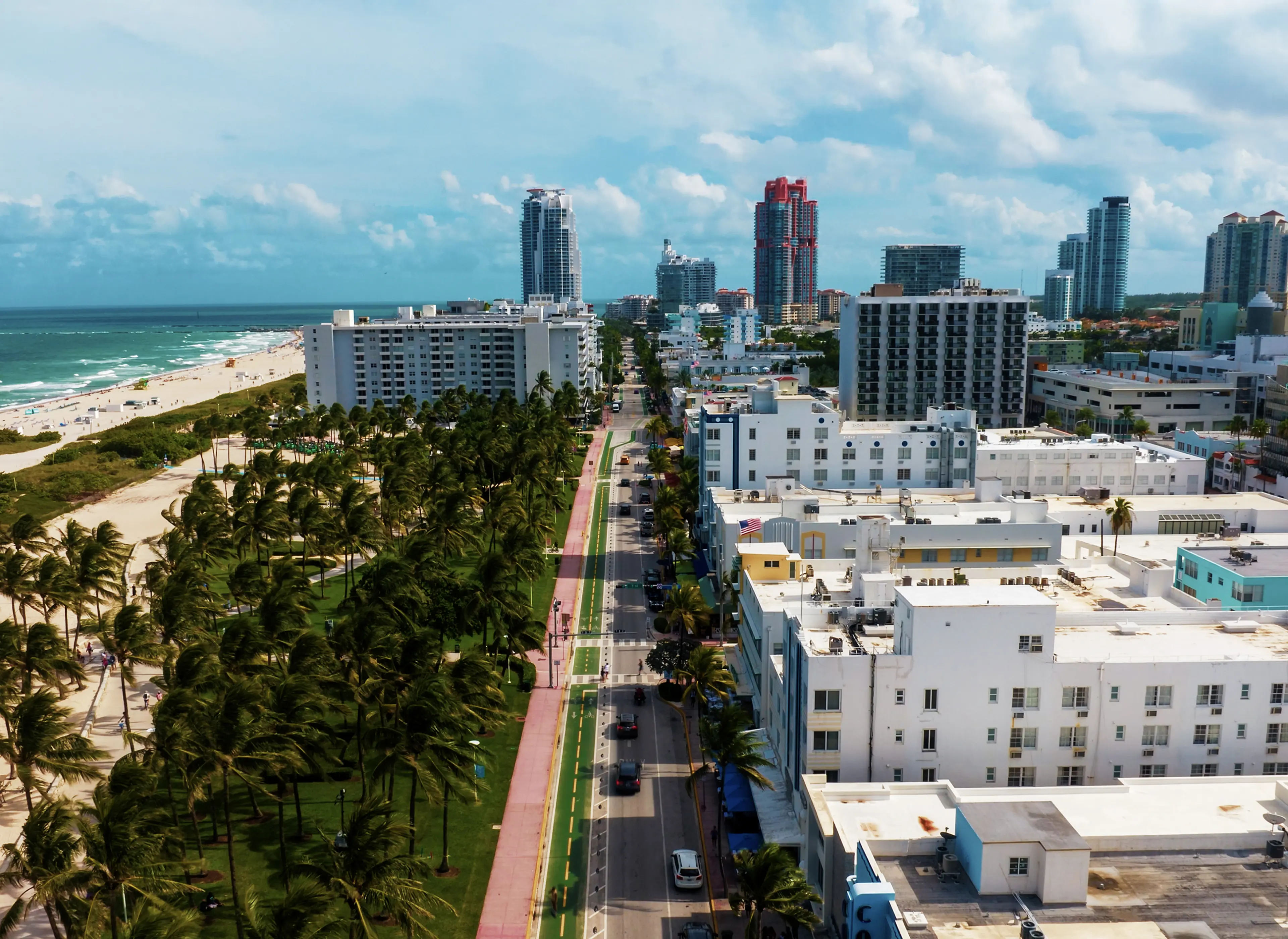 Aerial view of Miami Beach with palm-lined streets, white buildings and the ocean in the background.