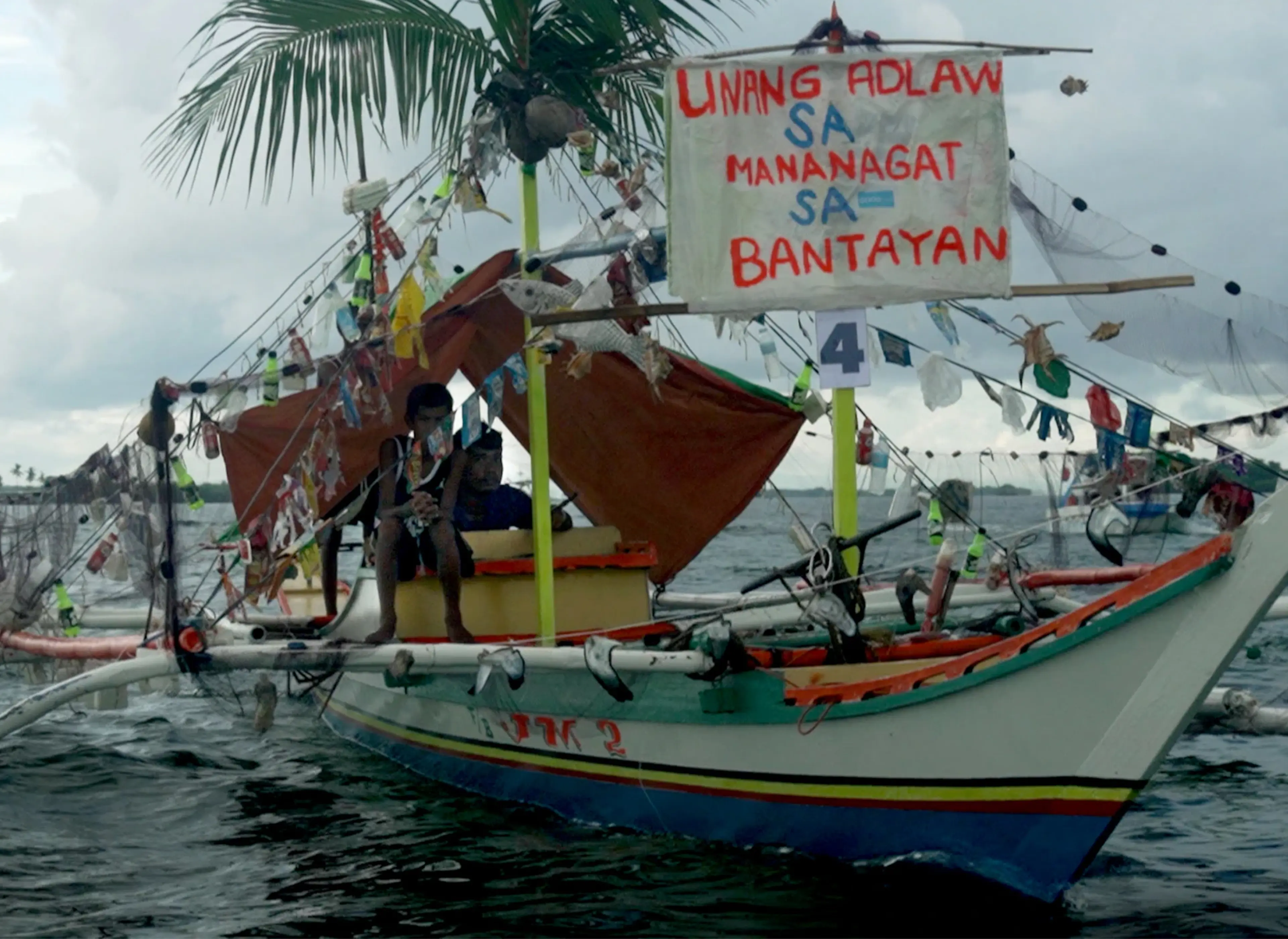 Fisherfolk, an artwork featuring a traditional fishing boat decorated with plastic waste to highlight ocean pollution.