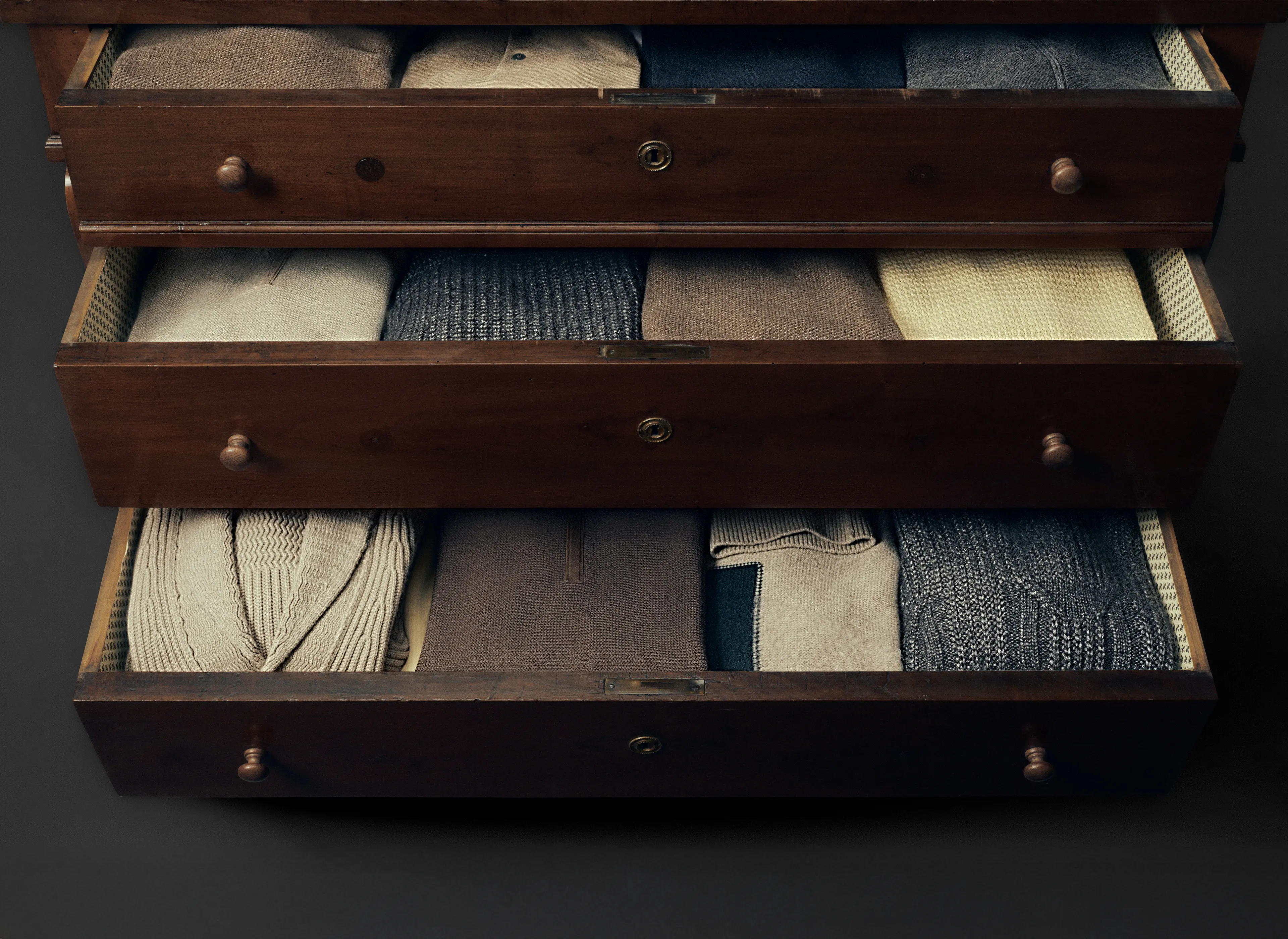 Stacked ZEGNA men’s sweaters in fine wool and luxury fabrics, folded in a wooden wardrobe.