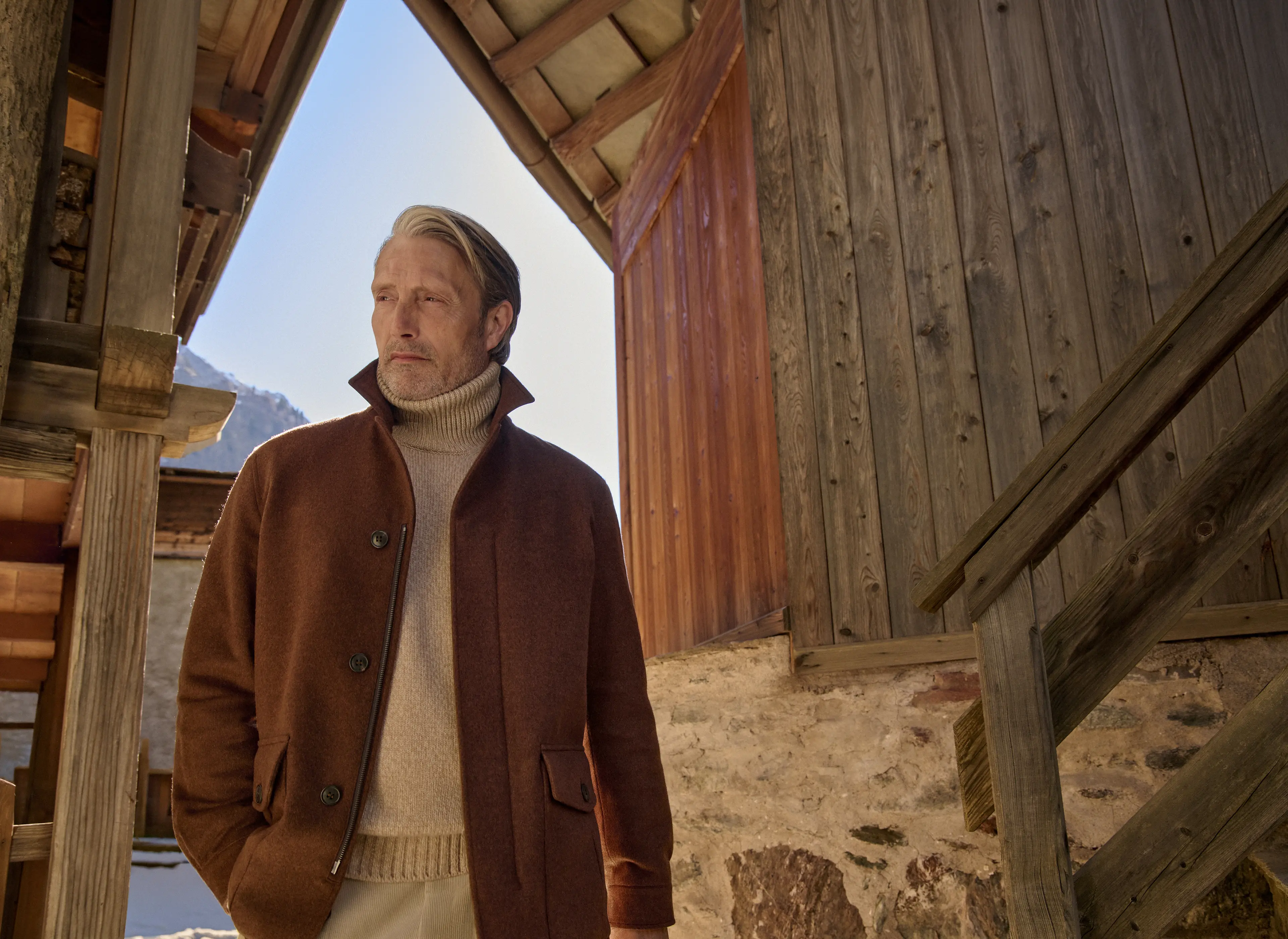 Mads Mikkelsen in der neuen Falcon Jacke aus rostbraunem Oasi Cashmere Elements mit Knopf- und Reißverschluss über einem cremefarbenen Rollkragenpullover aus der ZEGNA Herbst/Winterkollektion 2026.