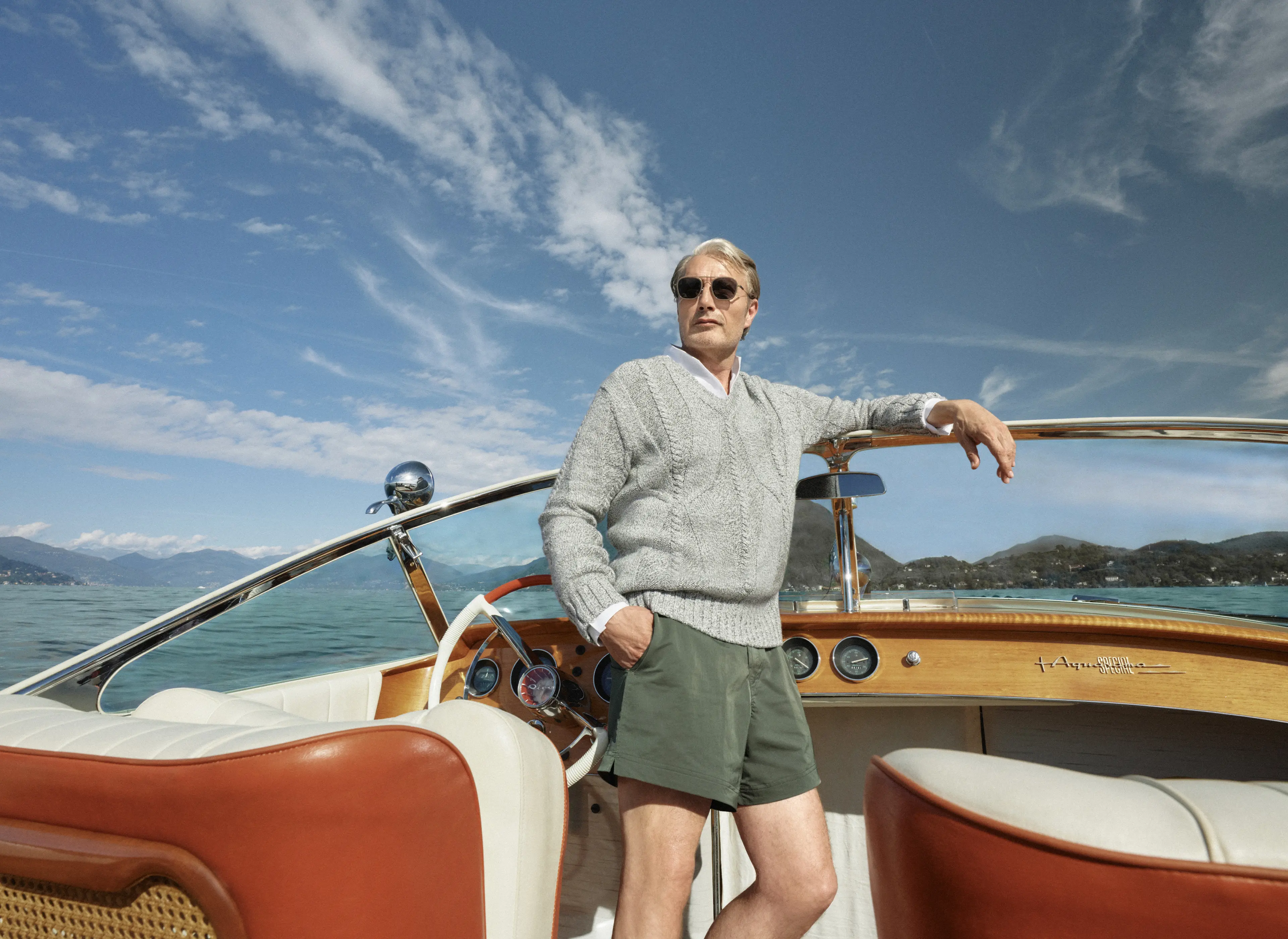 Mads Mikkelsen on a boat wearing a ZEGNA Spring Summer 2026 look featuring a V-neck sweater and the iconic Rio beachwear.