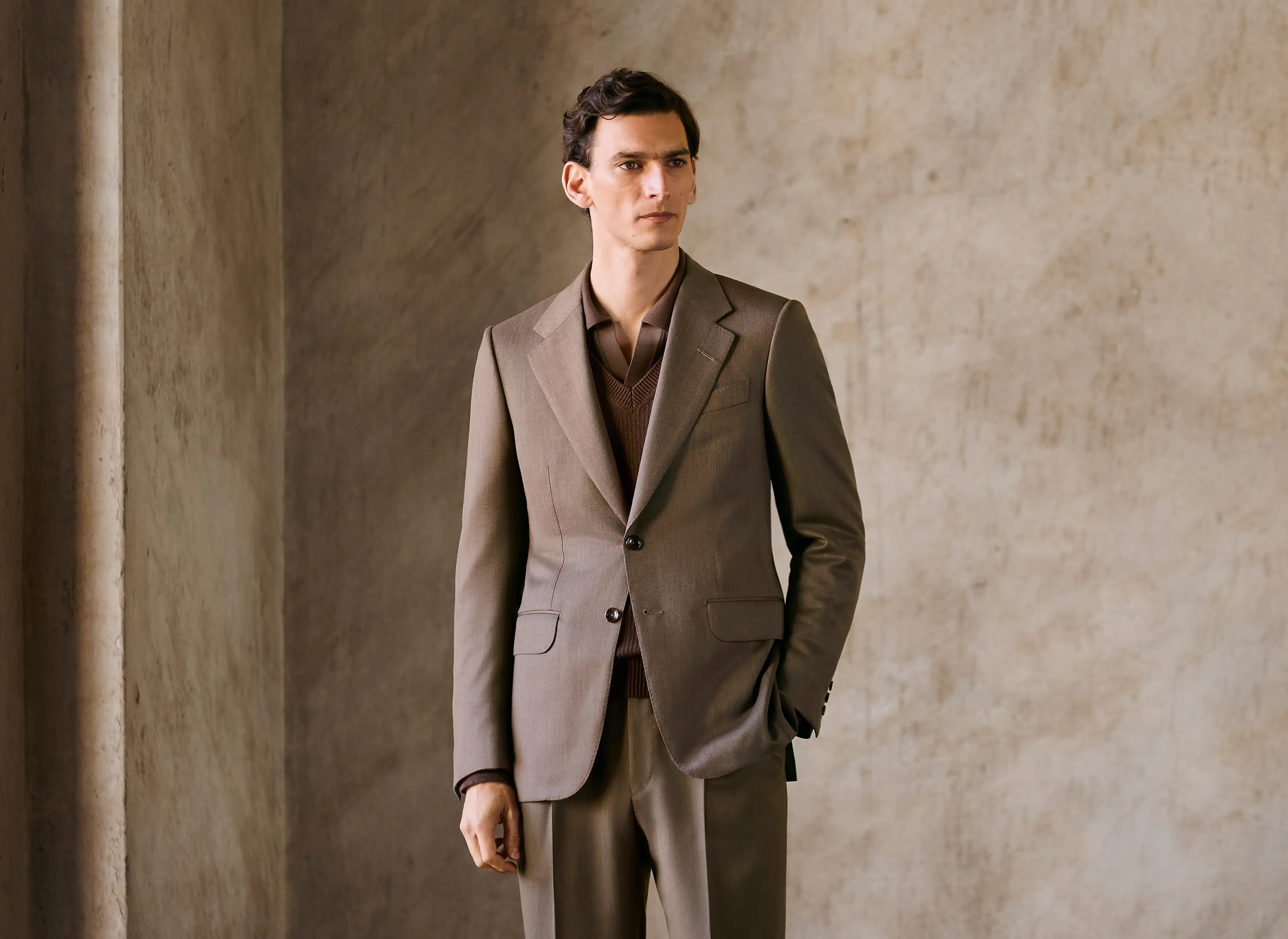 Homem a usar um fato elegante em tons de castanho, com casaco simples e calças com vinco da ZEGNA.