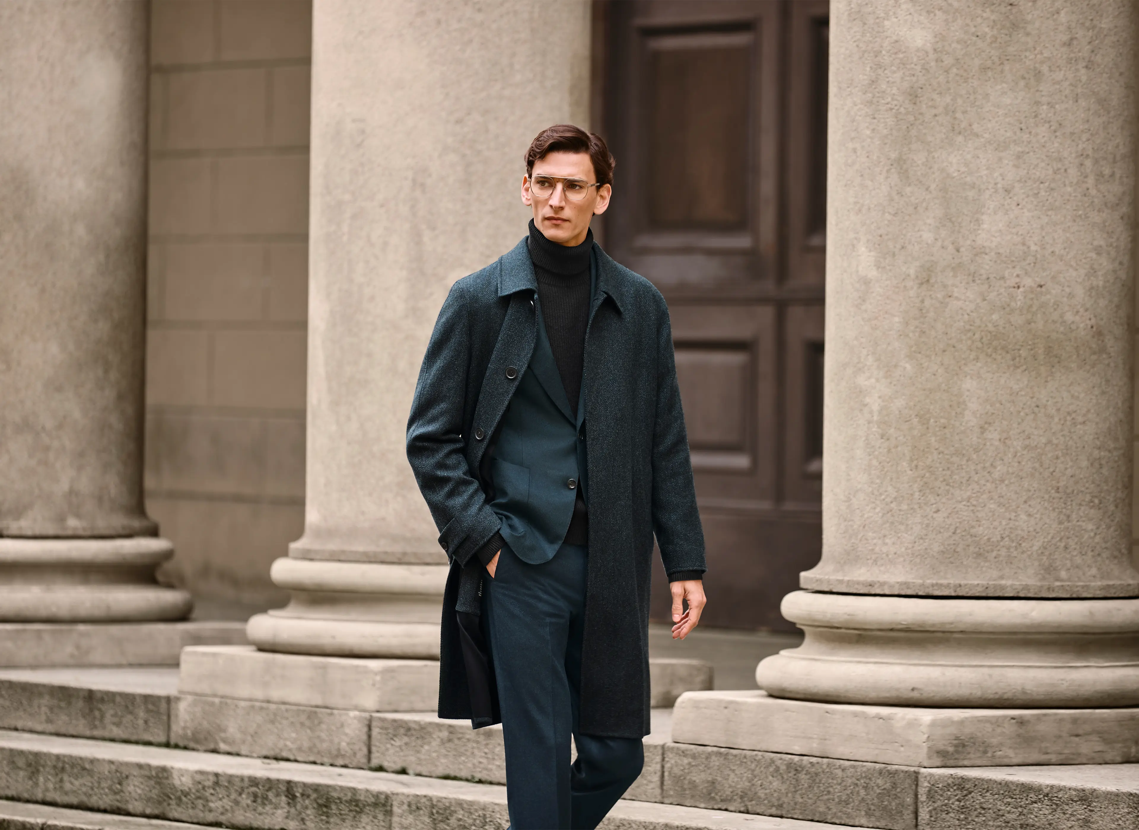 Homem com um look elegante, com casaco comprido, fato personalizado e camisola de gola alta em caxemira da coleção FW25 da ZEGNA.