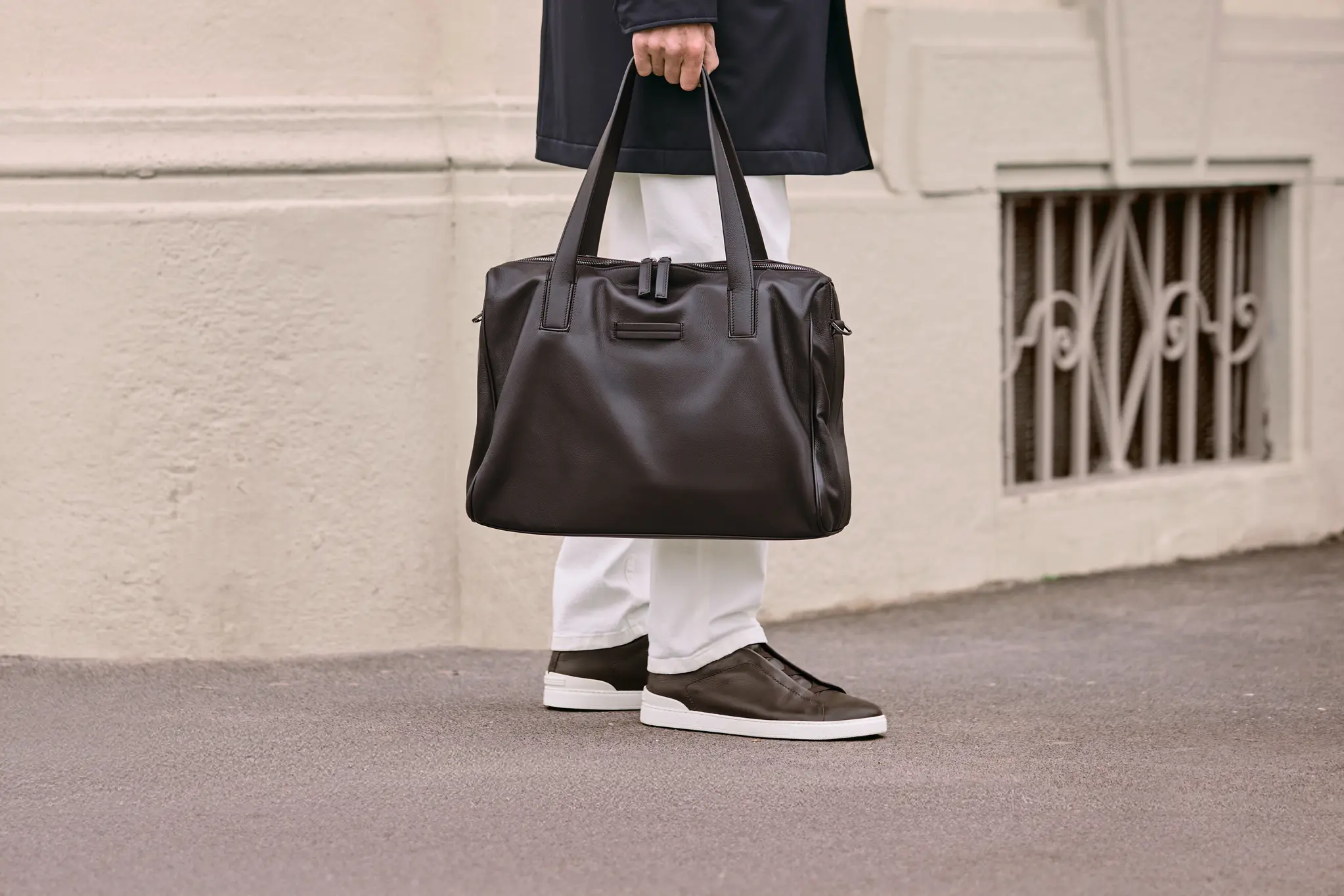Man carrying a luxury leather bag styled with a trench coat, from the ZEGNA Fall/Winter 2025 collection.