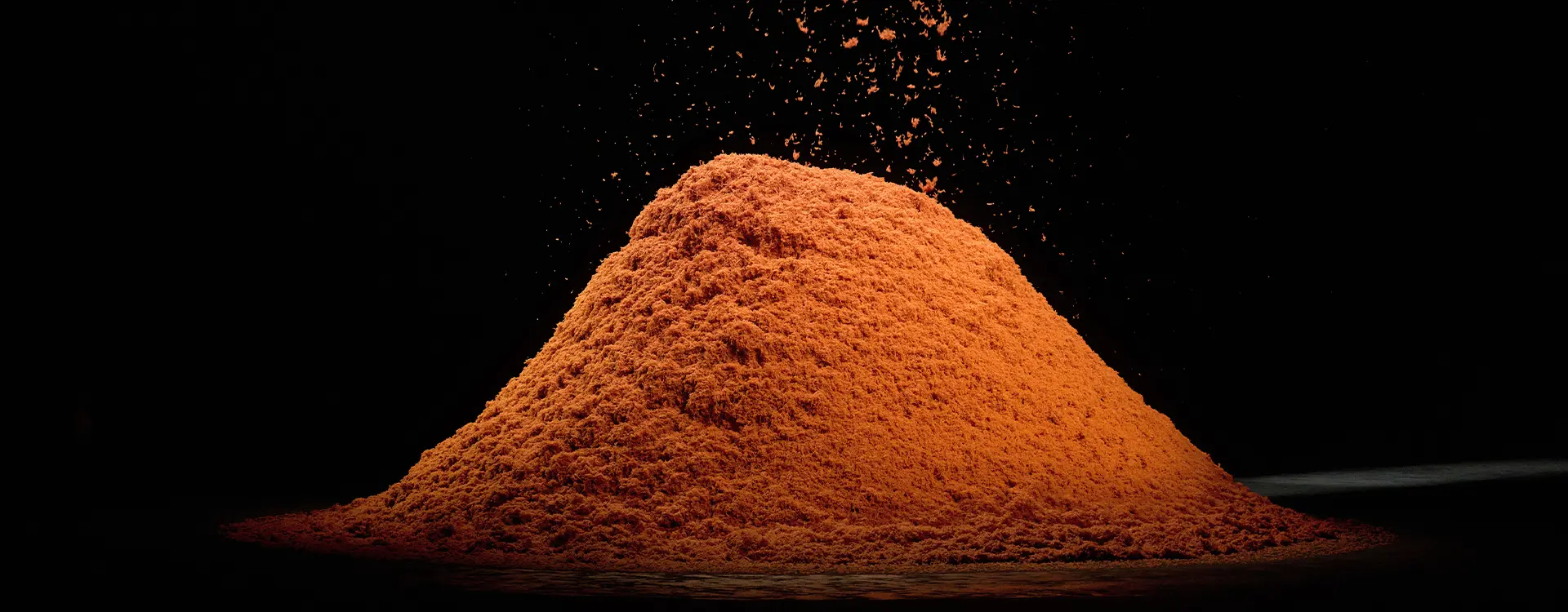 Une pile de fibres de cachemire orange vif disposées soigneusement sur fond noir.