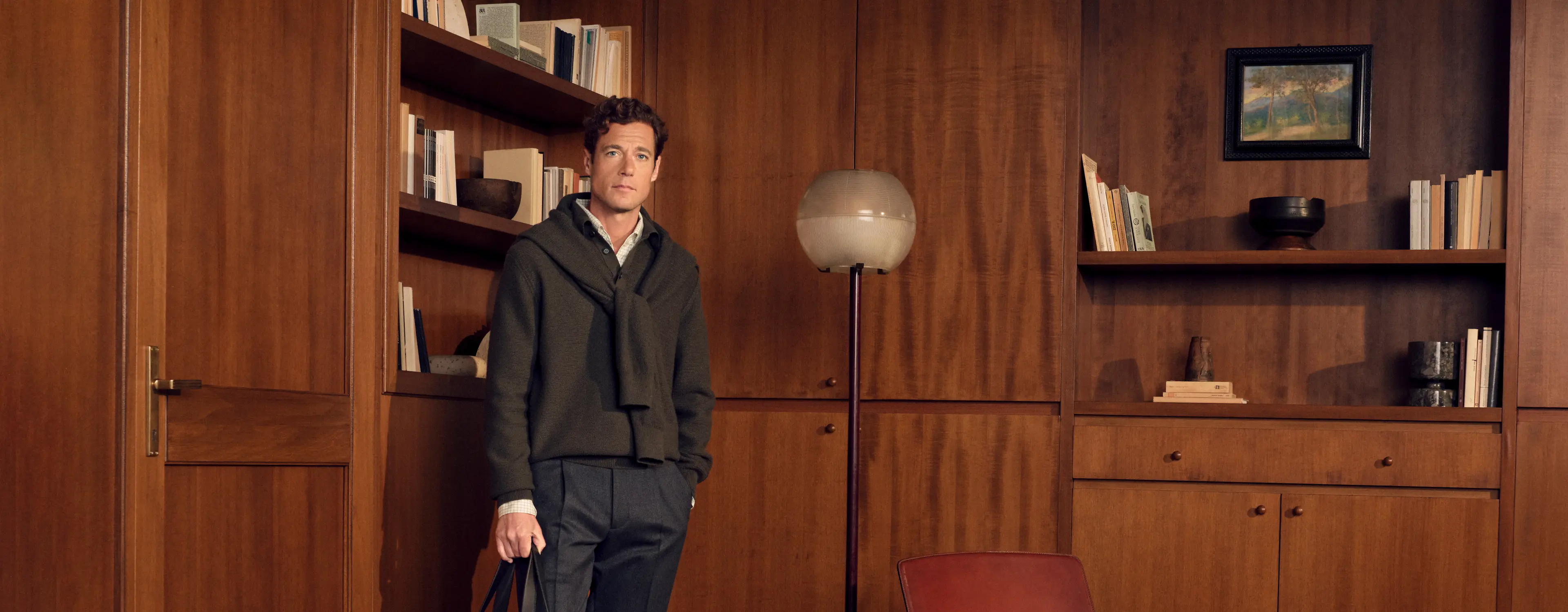 Man in an elegant casual look wearing the Cashseta crew neck in dark olive green with a Cashco shirt and wool and cashmere pants in dark grey, holding a Secondskin Weekender in dark brown, from the ZEGNA Fall/Winter 2026 collection.