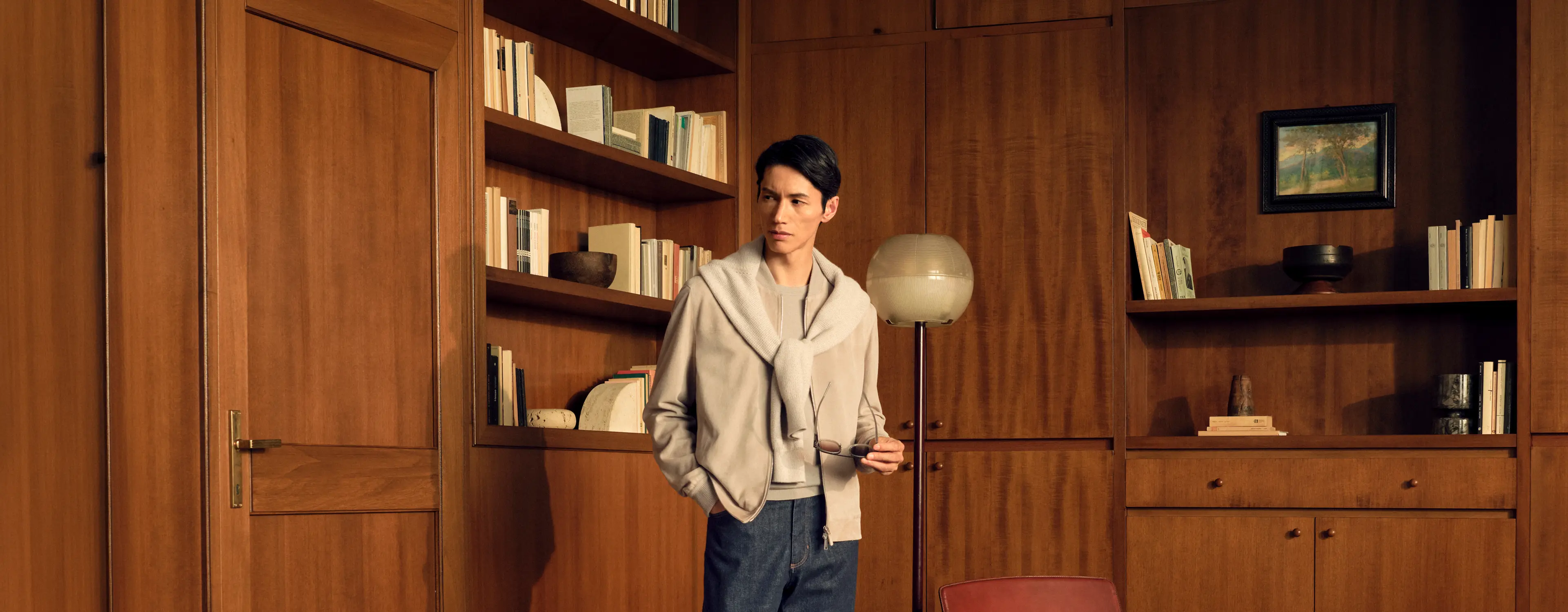 Man in a tonal look wearing the lamb suede bomber in light taupe with an Oasi Cashmere zip mock draped over the shoulders, a Cashseta crewneck and dark blue denim, from the ZEGNA Fall/Winter 2026 collection.