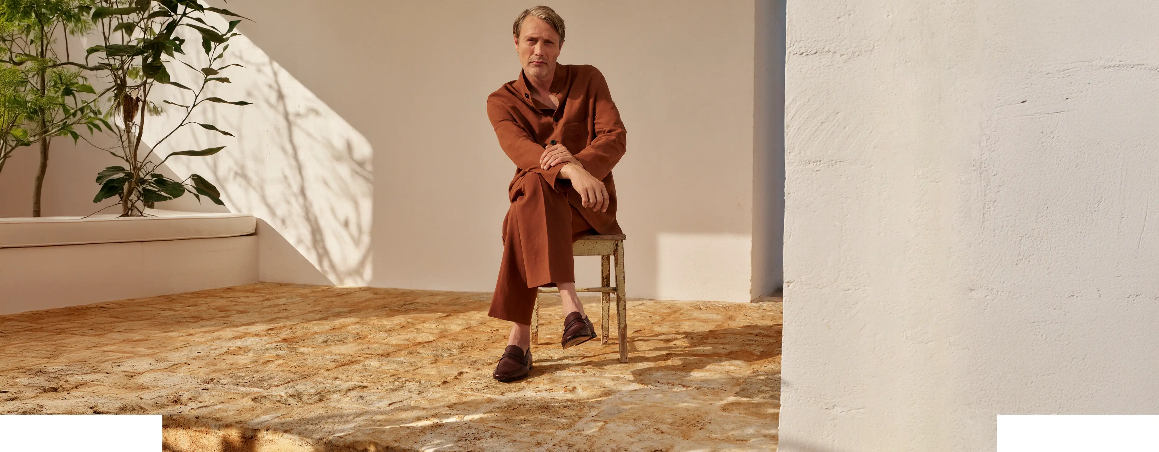 Mads Mikkelsen wearing a refined linen outfit in an earthy tone, paired with leather loafers, from the ZEGNA SS25 collection.